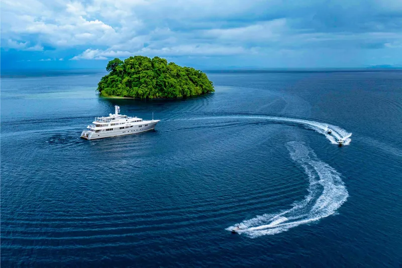 Dream Yacht Photos Pics Luxurious yacht cruising near a lush island, Abeking & Rasmussen 6430, 2001 model.