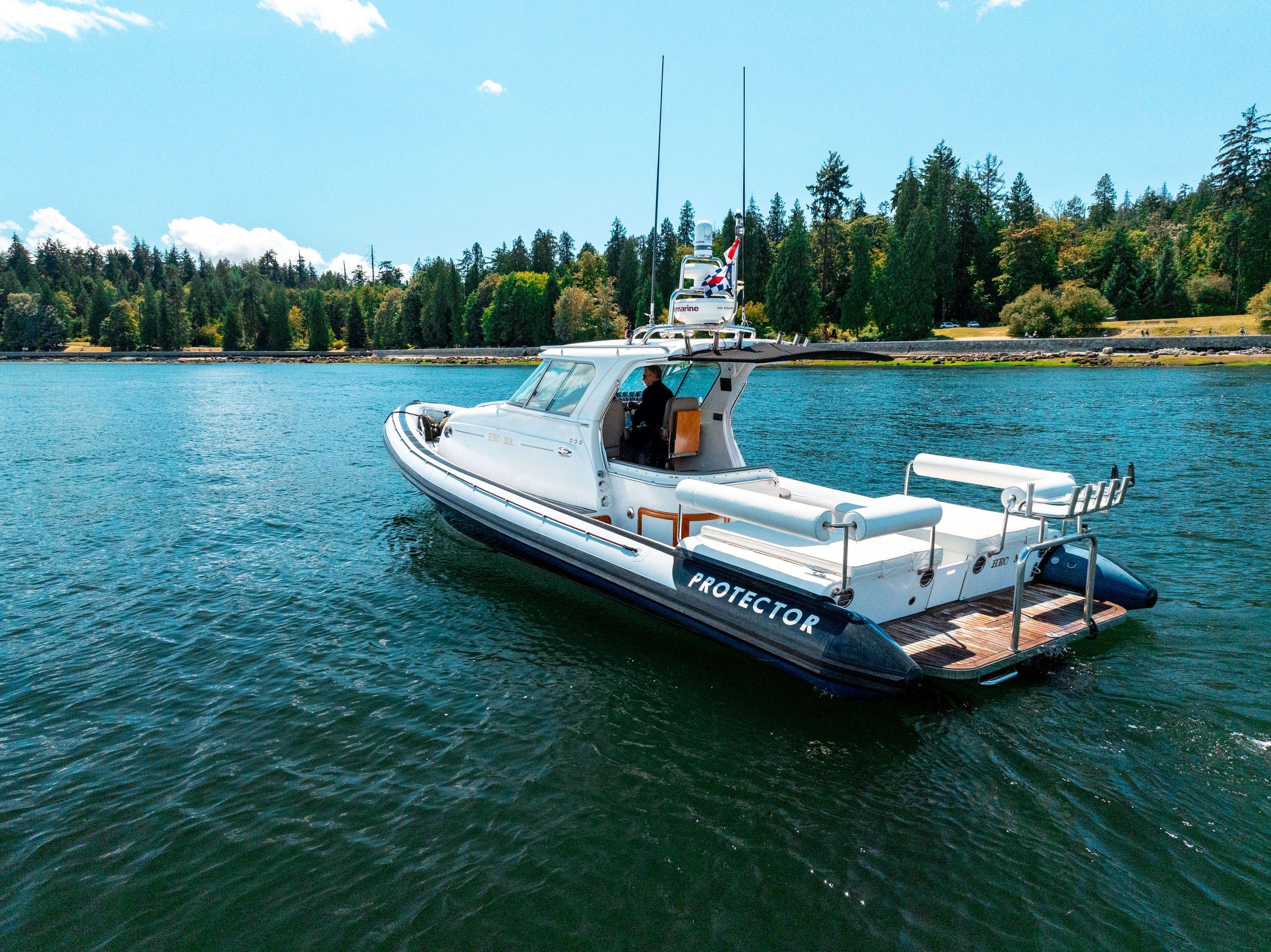 2009 Protector Targa 35 boat on a serene lake with forested shoreline.