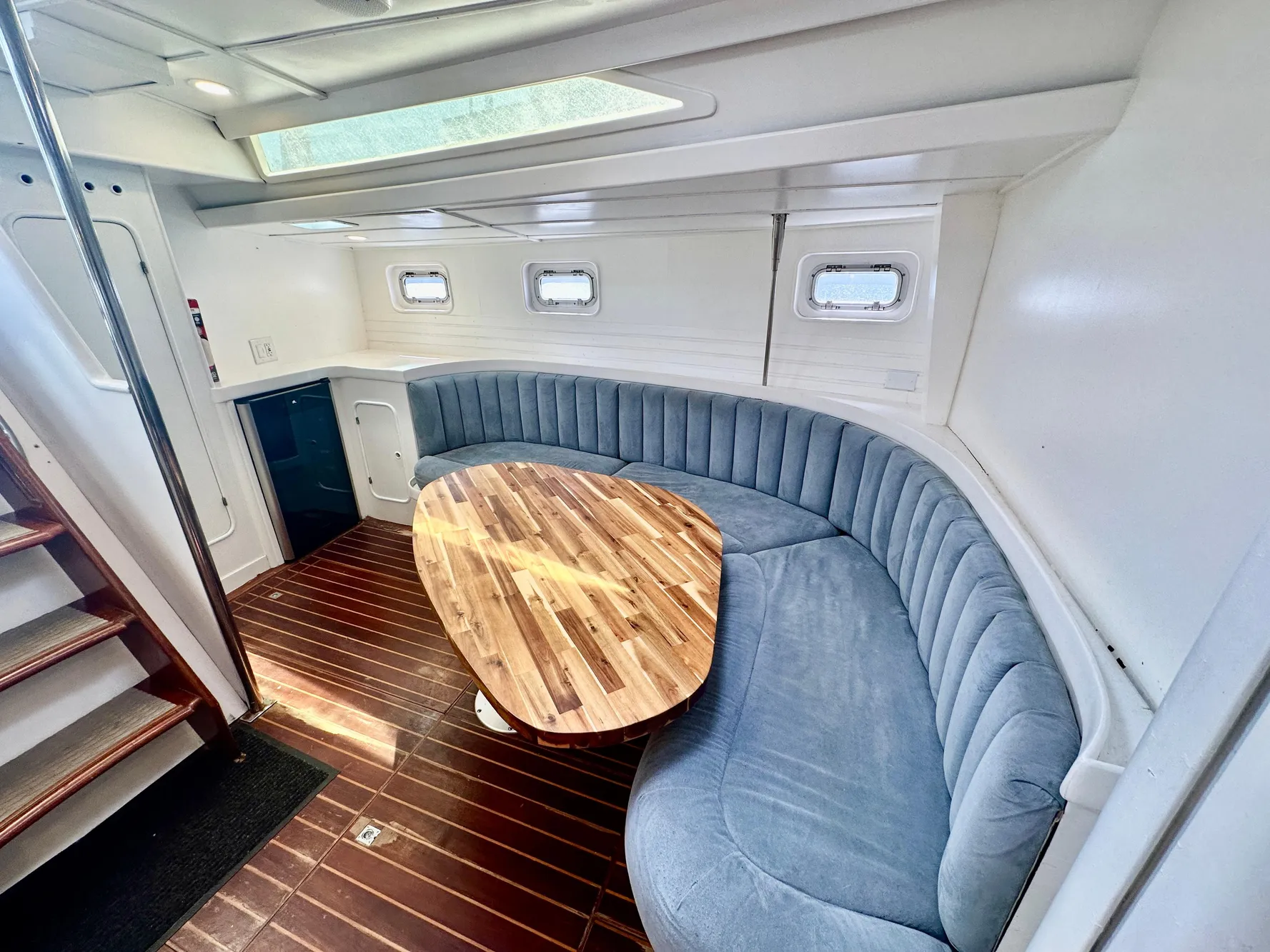 Luxurious 1983 Tayana 55 yacht interior with curved seating and wooden table.