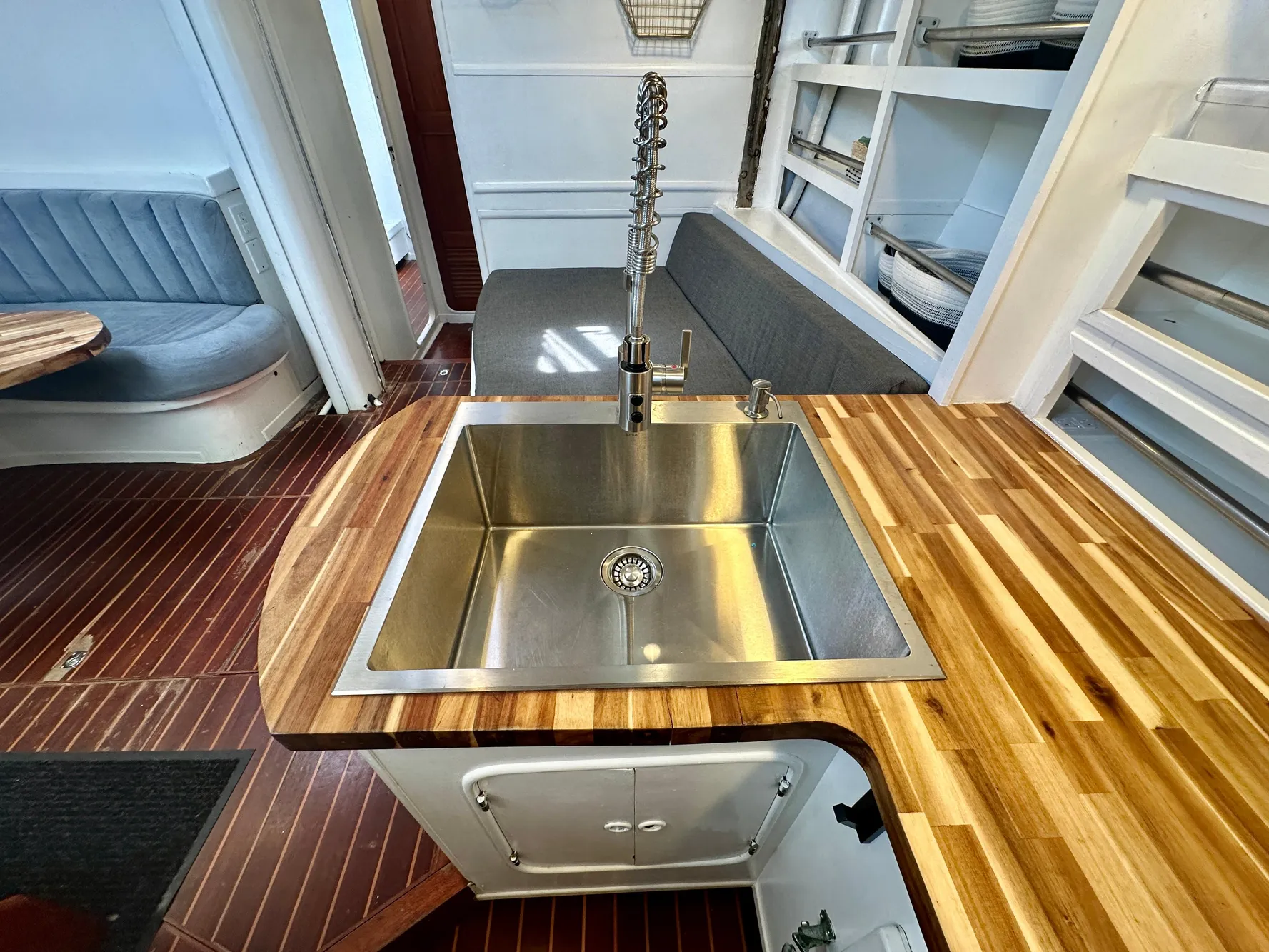 Modern kitchen interior on 1983 Tayana 55 yacht with stainless steel sink and wooden countertops.
