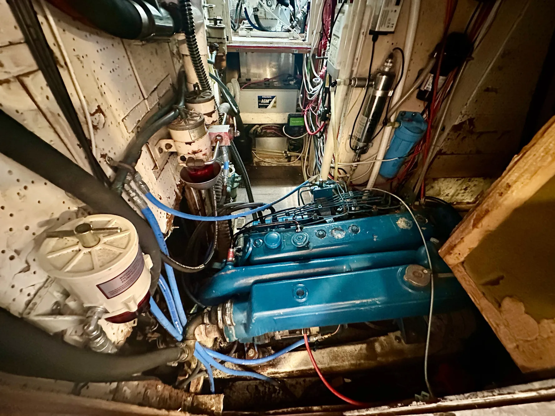 Engine room of a 1983 Tayana 55 yacht, featuring a blue engine and various mechanical components.
