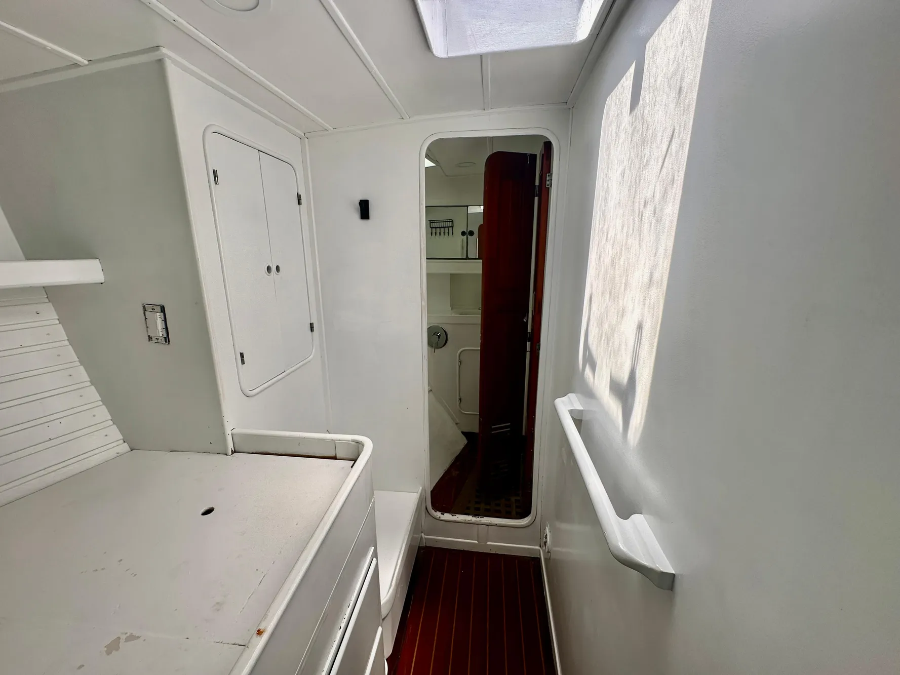 Interior of 1983 Tayana 55 yacht, featuring white walls, wooden floor, and natural light.