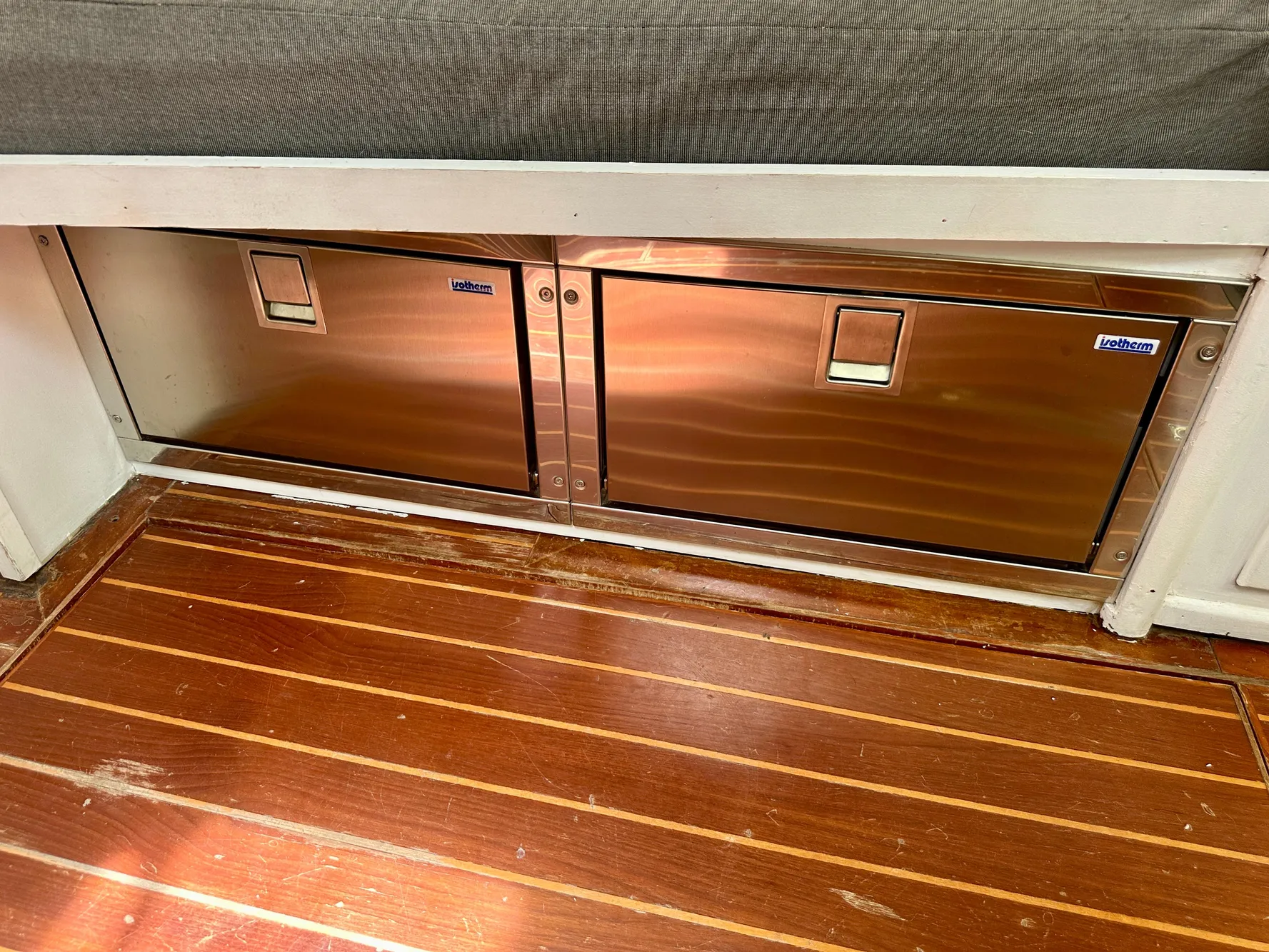 Stainless steel storage compartments on 1983 Tayana 55 yacht with wooden flooring.