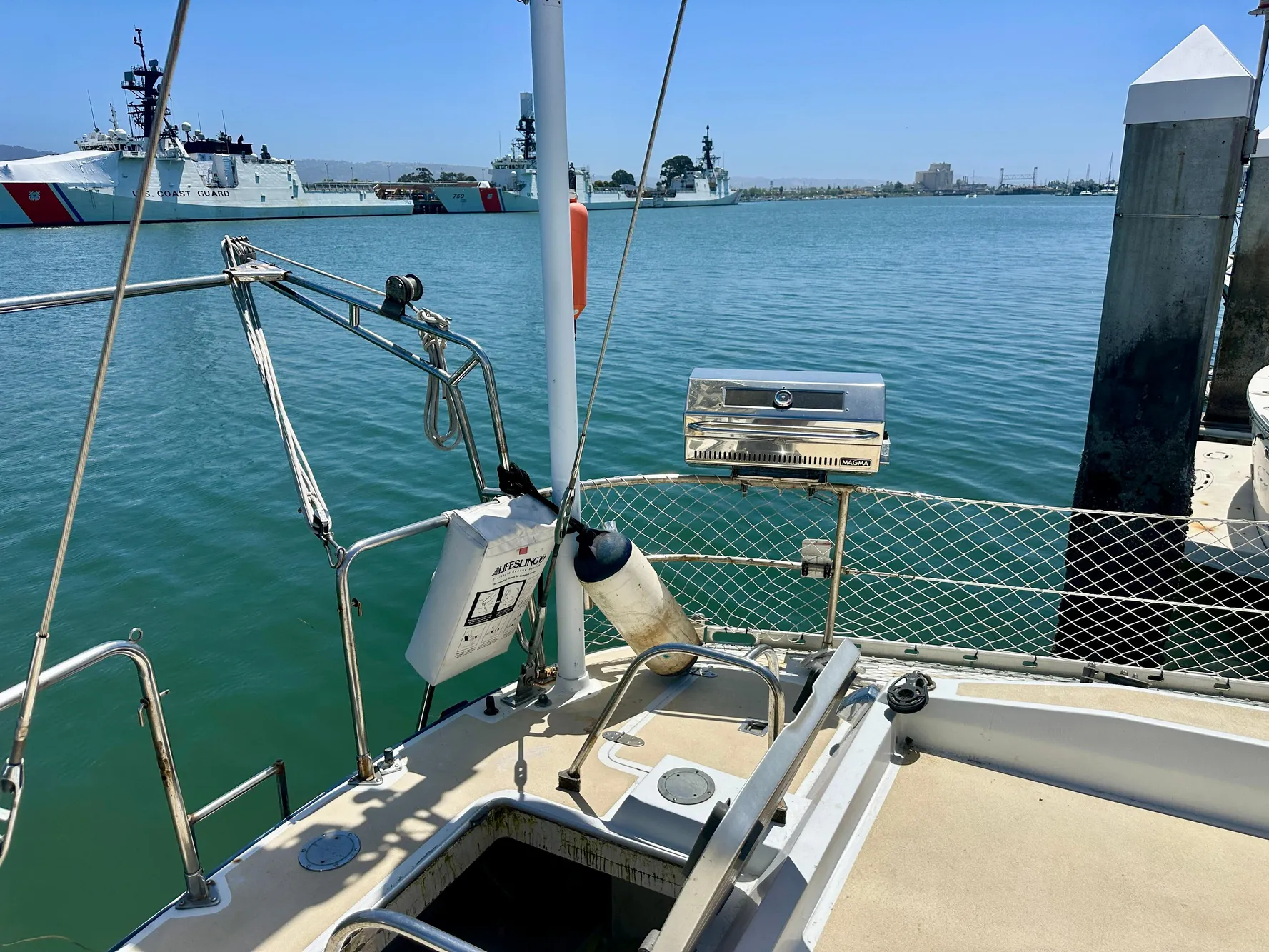 Sailboat deck view with grill, Tayana 55, 1983, docked near coast guard ships.