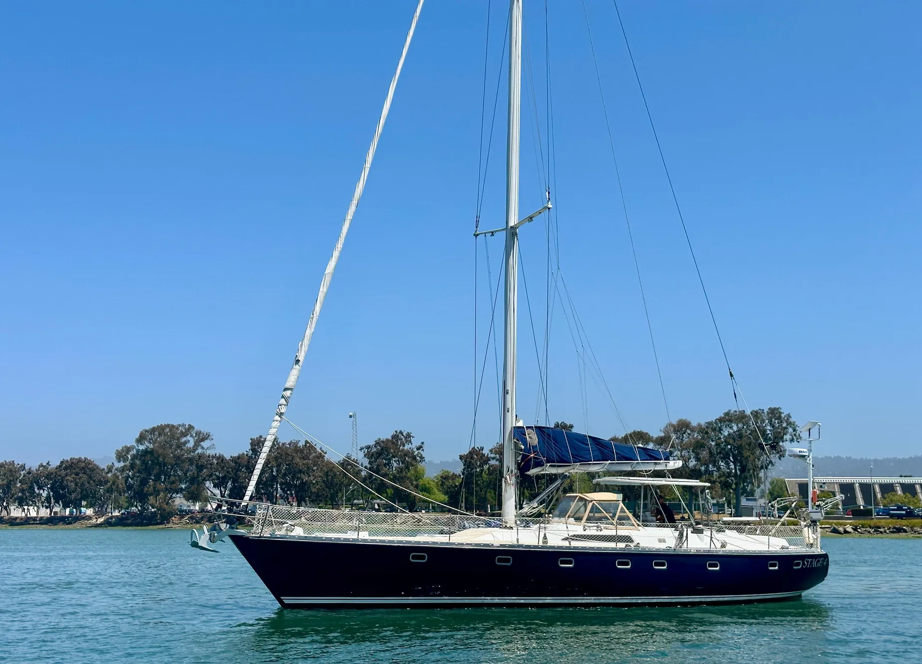 1983 Tayana 55 sailboat on calm water under clear blue sky.