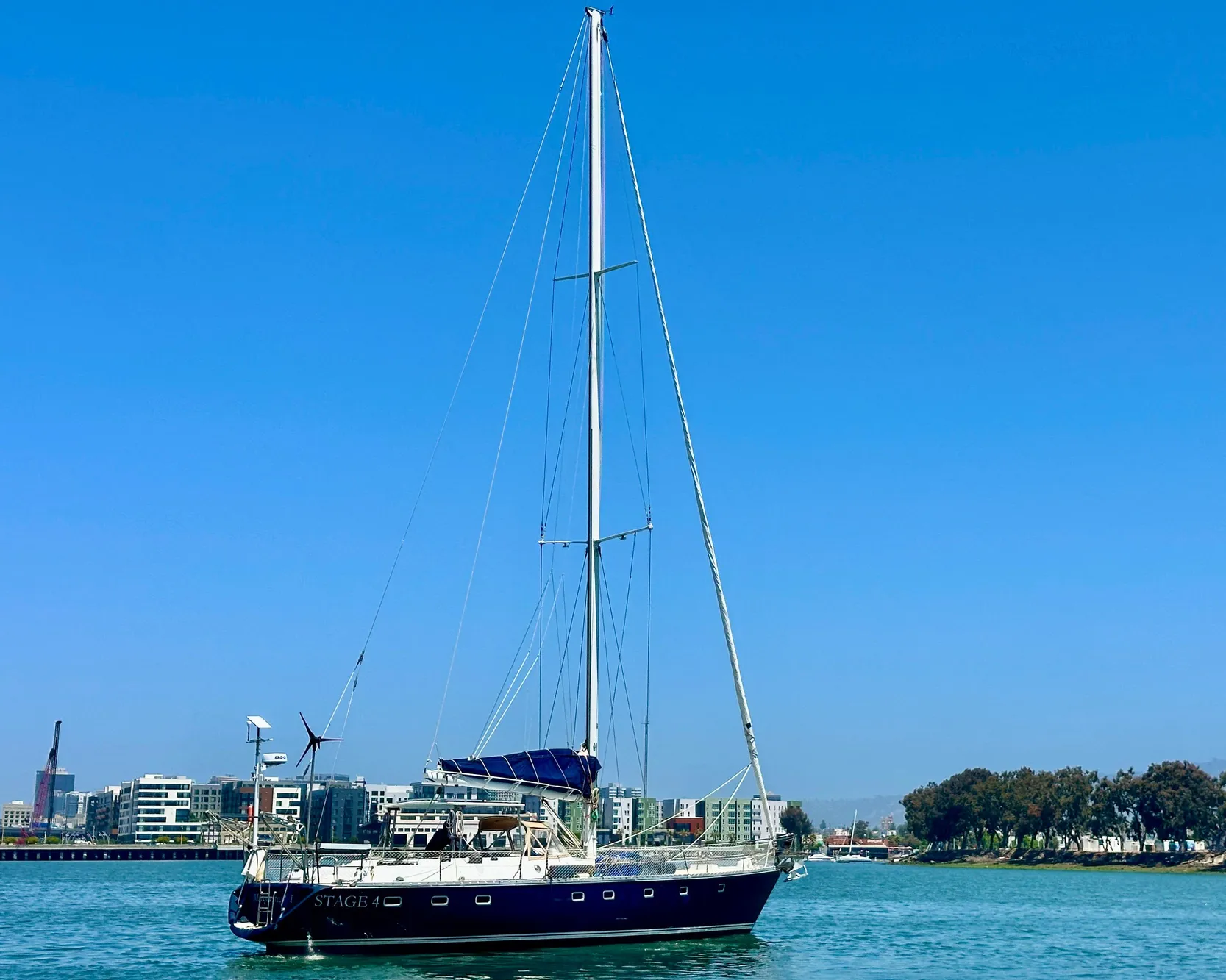 Sailing yacht Tayana 55, 1983 model, on calm waters with cityscape background.