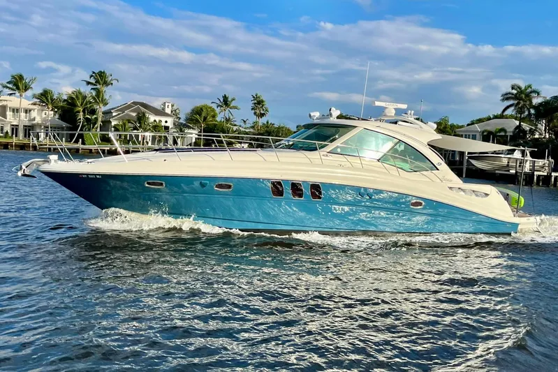 Knee Deep Yacht Photos Pics 2006 Sea Ray 48 Sundancer yacht cruising on a sunny day with palm trees in the background.