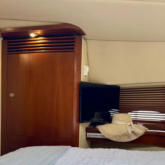 Knee Deep Yacht Photos Pics Interior of 2006 Sea Ray 48 Sundancer with wooden cabinetry, TV, and sun hat on bed.