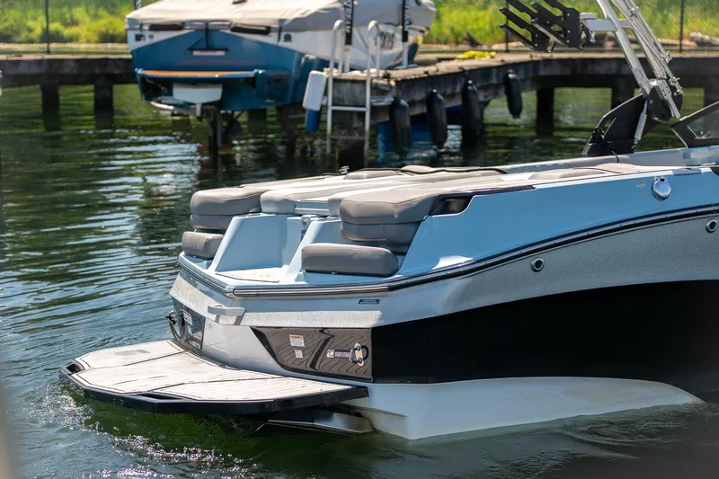  Yacht Photos Pics 2022 MasterCraft XT24 boat docked on calm water, showcasing sleek design and seating area.