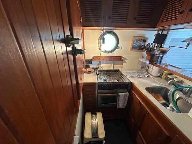 Tortuga Yacht Photos Pics Compact galley kitchen in 1987 Kadey-Krogen 42 boat with wooden cabinetry and porthole window.