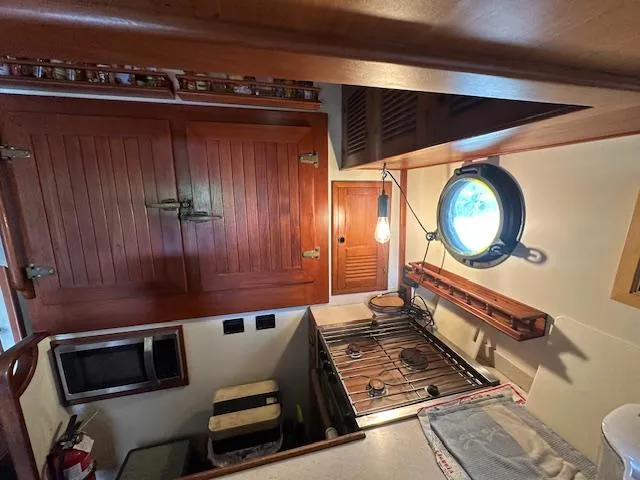 Tortuga Yacht Photos Pics Galley kitchen in 1987 Kadey-Krogen 42 boat with wooden cabinets and porthole window.