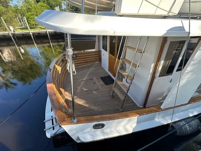 Tortuga Yacht Photos Pics 1987 Kadey-Krogen 42 yacht with wooden deck and ladder, docked by a calm waterway.