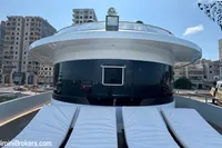 Luxurious 2024 Custom 29m Charter MY yacht with sun loungers, docked in an urban marina.