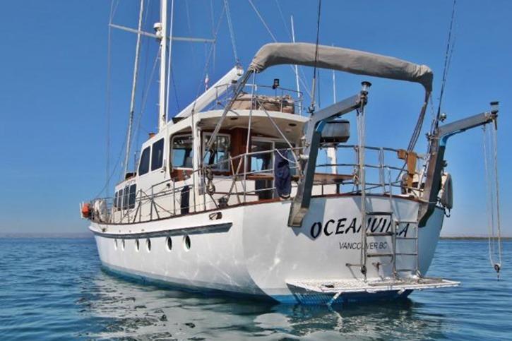 Custom Centre Cockpit Pilot House Steel Cutter Motorsailer, 1991, anchored in calm blue waters.