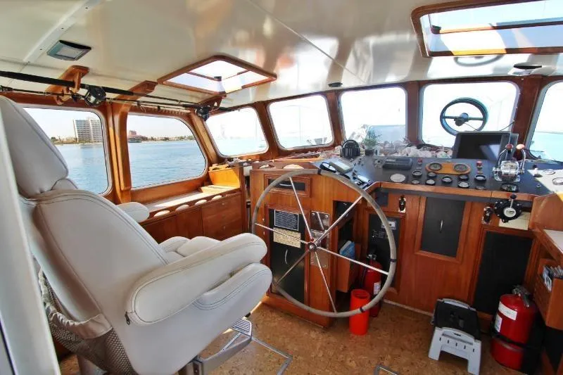 Ocean Villa Yacht Photos Pics Centre cockpit of a 1991 Custom Motorsailer with wooden interior and large steering wheel.