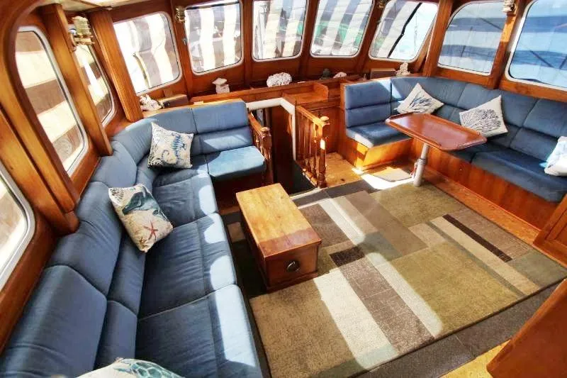 Ocean Villa Yacht Photos Pics Luxurious interior of a 1991 Custom Centre Cockpit Pilot House Motorsailer with blue seating.