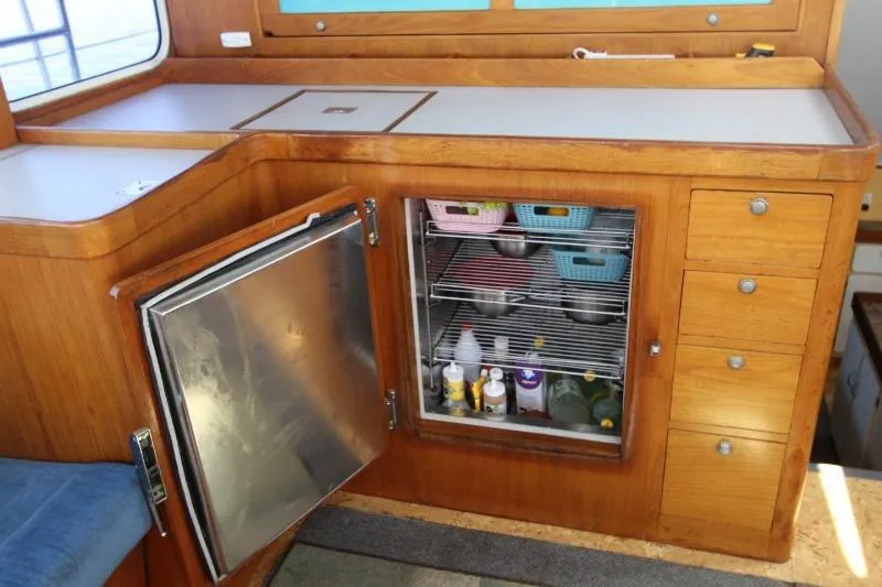 Ocean Villa Yacht Photos Pics Interior of 1991 Custom Motorsailer with open fridge, wooden cabinetry, and organized storage.