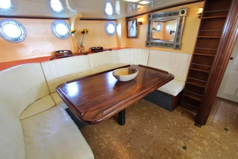 Ocean Villa Yacht Photos Pics Luxurious interior of 1991 Custom Centre Cockpit Motorsailer with elegant dining area and porthole windows.