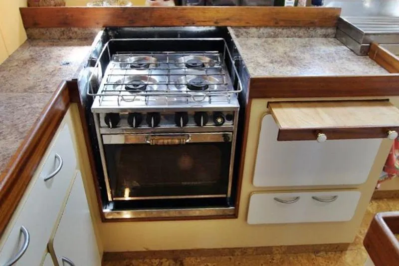 Ocean Villa Yacht Photos Pics 1991 Custom Motorsailer kitchen with stove, wooden countertops, and storage cabinets.