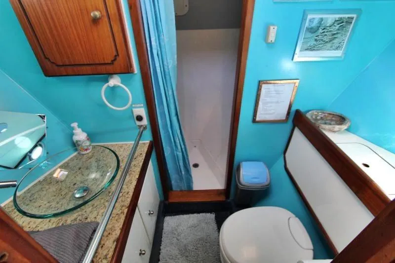 Ocean Villa Yacht Photos Pics Bathroom interior of 1991 Custom Centre Cockpit Pilot House Steel Cutter Motorsailer, featuring turquoise walls.