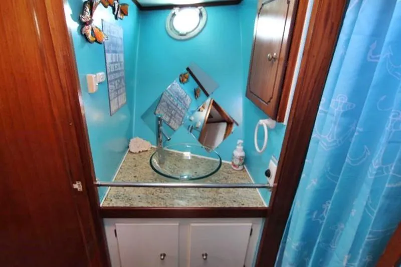 Ocean Villa Yacht Photos Pics Small bathroom with turquoise walls, glass sink, and nautical decor on a 1991 motorsailer.