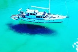 Ocean Villa Yacht Photos Pics Custom 1991 steel cutter motorsailer in clear turquoise water, aerial view.