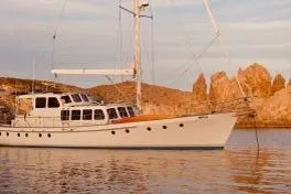 Ocean Villa Yacht Photos Pics Custom 1991 Centre Cockpit Pilot House Steel Cutter Motorsailer on calm water at sunset.