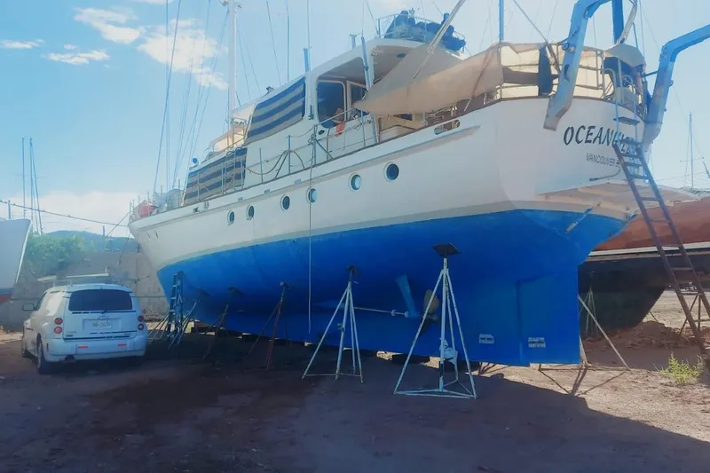 Ocean Villa Yacht Photos Pics Custom 1991 Centre Cockpit Pilot House Steel Cutter Motorsailer on dry dock with car nearby.