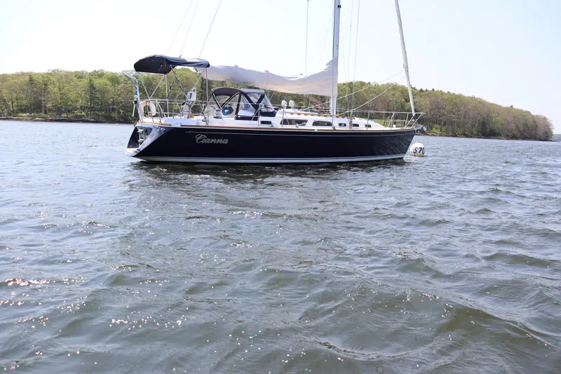 Cianna Yacht Photos Pics 2001 Sabre 402 sailboat on calm water with forested shoreline in the background.