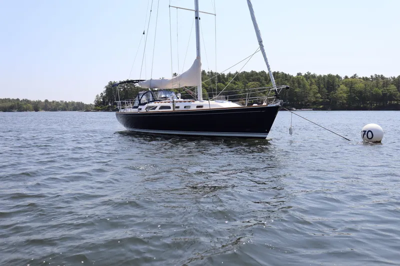 Cianna Yacht Photos Pics 2001 Sabre 402 sailboat anchored on calm water near a forested shoreline.