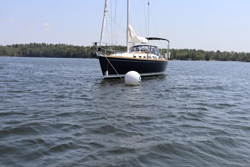 Cianna Yacht Photos Pics Sailboat Sabre 402 (2001) anchored on a calm lake with forested shoreline.