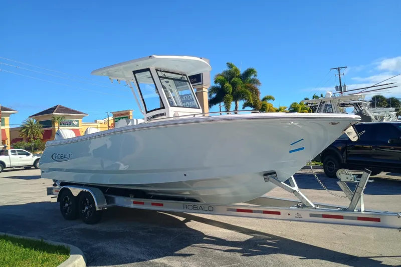 250-118 Yacht Photos Pics 2026 Robalo R250 Center Console boat on trailer, parked outdoors under clear blue sky.