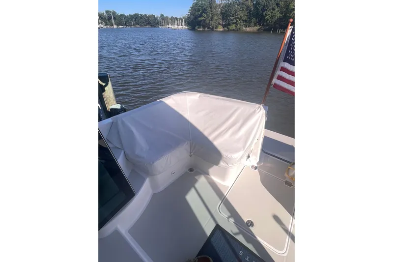 Selah Yacht Photos Pics 2012 Back Cove 37 boat deck with covered seating and American flag on a calm river.
