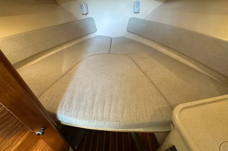 Yacht Photos Pics 2006 Pursuit 3070 Offshore cabin interior with beige cushions and wooden flooring.