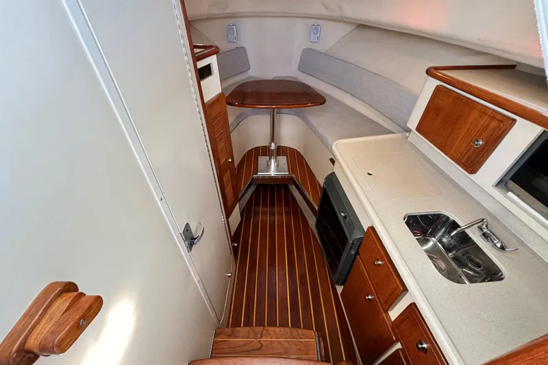  Yacht Photos Pics 2006 Pursuit 3070 Offshore cabin interior with wood accents and compact kitchen area.