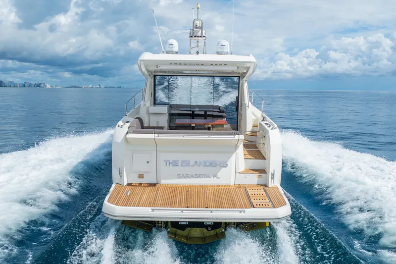  Yacht Photos Pics 2018 Prestige 520S yacht cruising on open water, rear view, with city skyline in background.