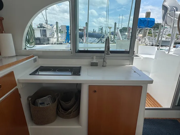 Wylicat Yacht Photos Pics Interior view of Lagoon 380 catamaran kitchen with stove and sink, overlooking marina.