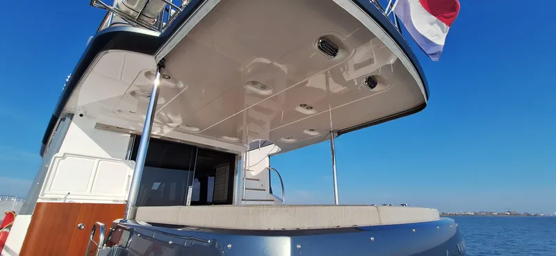 Bella Vita Yacht Photos Pics Azimut Magellano 66 yacht, 2020 model, rear view with flag, clear blue sky.