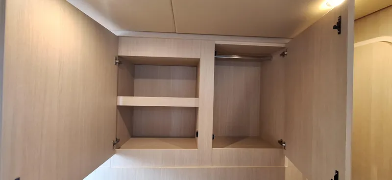 Bella Vita Yacht Photos Pics Open wooden cabinet inside 2020 Azimut Magellano 66 yacht, featuring shelves and storage space.