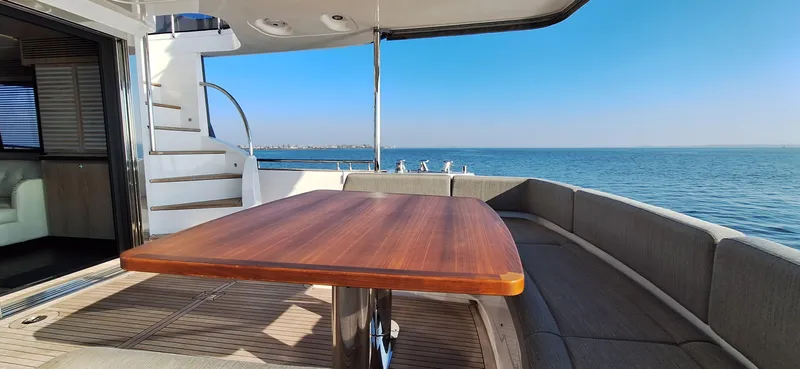 Bella Vita Yacht Photos Pics Azimut Magellano 66 yacht deck with wooden table, ocean view, and curved seating, 2020 model.