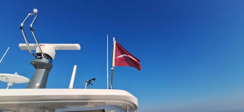 Bella Vita Yacht Photos Pics 2020 Azimut Magellano 66 yacht with a red flag against a clear blue sky.