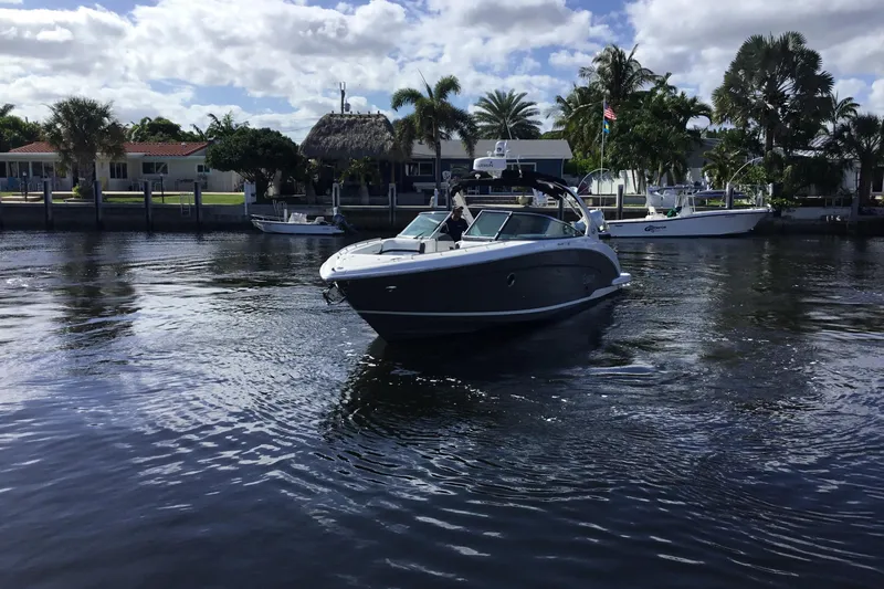 Enbarr Yacht Photos Pics 2017 Regal 3200 Bowrider cruising on a sunny waterfront with palm trees.