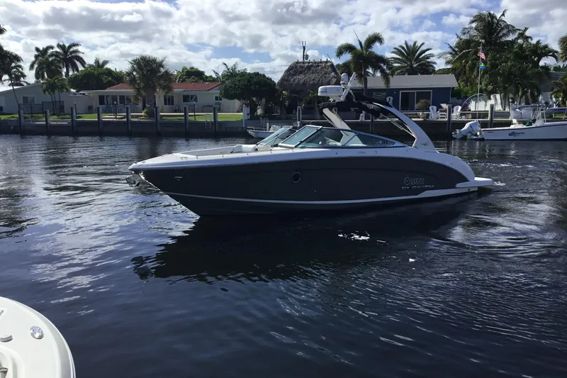 Enbarr Yacht Photos Pics 2017 Regal 3200 Bowrider boat cruising on a sunny waterfront with palm trees.