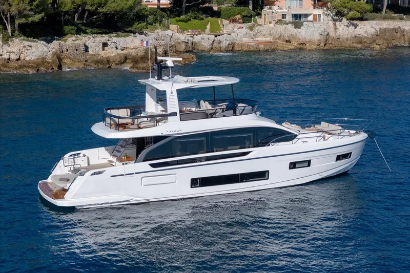  Yacht Photos Pics 2025 Azimut Fly 62 yacht cruising in clear blue waters near rocky coastline.