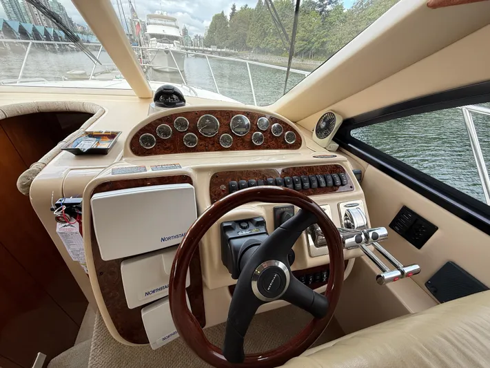 Diamonds Wild Yacht Photos Pics 2006 Meridian 411 Sedan helm with wood accents and modern controls, docked by a scenic waterfront.