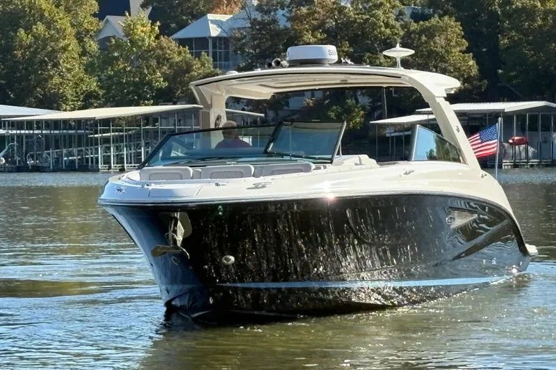  Yacht Photos Pics 2023 Sea Ray SLX 400 boat cruising on a serene lake with docked boats in the background.
