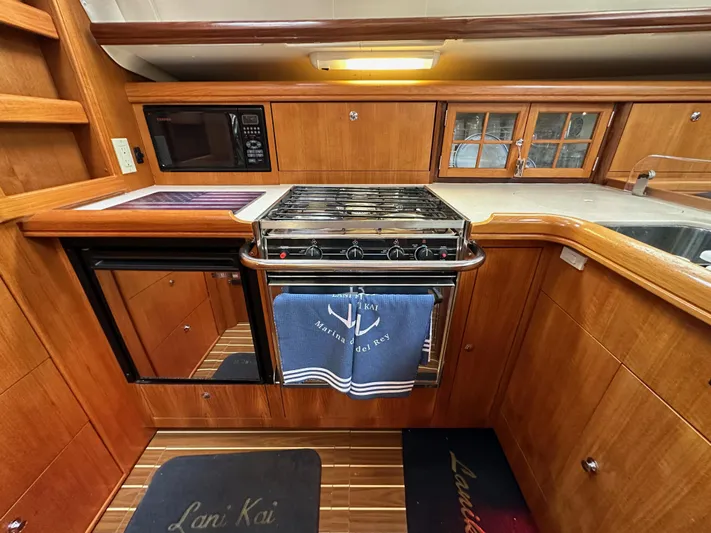 Lanikai Yacht Photos Pics 2007 Hunter 44 Deck Salon kitchen with wood cabinetry, stove, microwave, and nautical-themed decor.