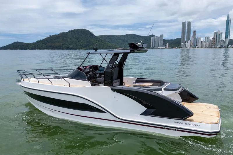  Yacht Photos Pics Modern 2026 GRAND OCEAN 37 yacht cruising near a city skyline and lush hills.