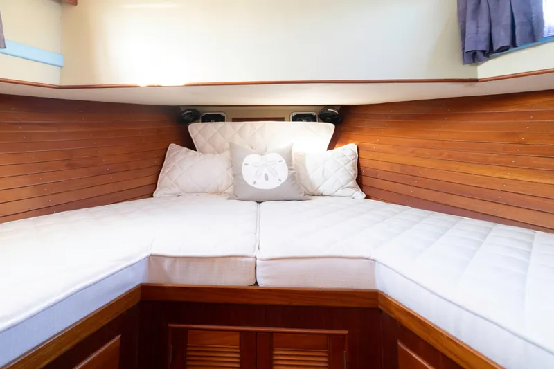 Cheers Yacht Photos Pics Cozy cabin interior of 1989 Grand Banks 46 Classic yacht with wooden paneling and white bedding.