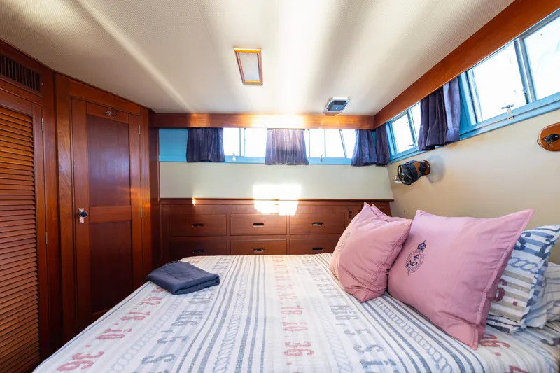 Cheers Yacht Photos Pics Cozy bedroom interior of 1989 Grand Banks 46 Classic yacht with wood paneling and nautical decor.
